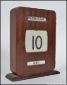 A vintage 1950's teak wood desk top calendar with rollers having the paper rollers intact.