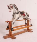 A 20th century rocking horse of wooden construction with painted dapple grey finish having glider