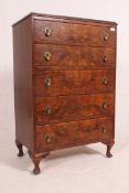 A 1930's Art Deco walnut chest of drawers being raised on cabriole legs with 5 drawers having brass