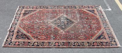 A 20th century handwoven Persian rug with central single diamond medallion centre over red and blue