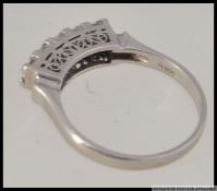 A platinum and diamond 5 stone ring with 5 princess cut diamonds in a scrolled gallery setting.