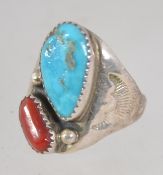 A vintage sterling silver ring set with a turquoise and coral in a brutalist setting with etched
