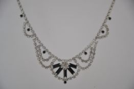 A vintage black and white rhinestone necklace in a silver tone metal setting with spring hoop clasp