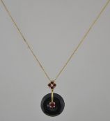 A hallmarked 9ct gold obsidian and ruby pendant necklace with obsidian disk set with a central ruby