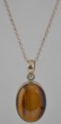 A 925 silver pendant necklace with tigers eye cabochon pendant in a rub over setting. Marked 925.