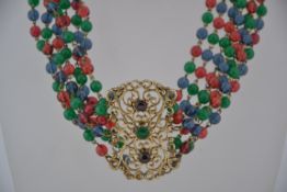 A vintage 1970s seven strand glass bead choker necklace with a gold tone central panel set with