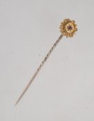 A Victorian 15ct gold stick pin with central ruby in a star cut setting surrounded by filigree,
