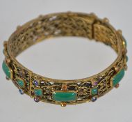A vintage 1920s Czech filigree gold tone hinged bangle with coloured rhinestones and glass faux