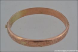 A hallmarked 9ct gold bangle bracelet with foliate scroll decoration with clip and safety clasp.
