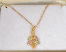 A Landstroms 10ct gold pendant necklace with tri colour gold grapevine pendant in original