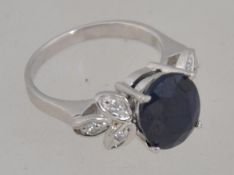 A silver cz and large real sapphire dress ring. the large oval cut sapphire with cz leaf borders.