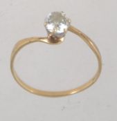 A hallmarked 9ct gold ring with a large prong set clear stone approx 25pts on a cross over band.
