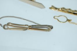 A pair of vintage yellow metal shirt cuffs together with three yellow metal tie clips and a pair