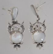 A pair of silver and moonstone earrings in the form of owls having teardrop moonstone studs.