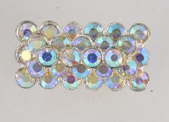 A vintage white metal brooch pin set with Aurora Borealis rhinestones with roller clip clasp.