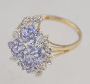 A hallmarked 9ct white gold ring set with tanzanite and diamonds in a prong set foliate cluster.