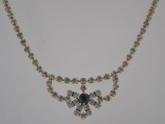 A vintage 1950's rhinestone festoon prom necklace set with round cut blue tone stones with spring