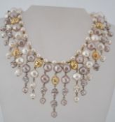 A vintage faux pearl bib necklace in shades of white and oyster grey with gold tone filigree beads