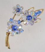 A vintage gold tone flower spay brooch set with white and blue aurora finish faceted beads with