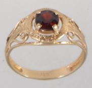 A hallmarked 9ct gold ring set with a single large round cut garnet in a prong setting with pierced