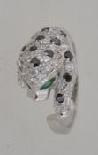 A contemporary ladies silver Cartier style panther ring adorned with green garnet stones.
