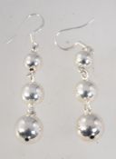 A pair of sterling silver graduated ball earrings. Marked 925. 5cm drop.