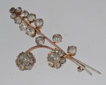 A vintage white metal flower spray brooch set with clear rhinestones and roller clasp.