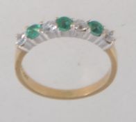A hallmarked 9ct gold ring set with alternating green and clear stones. Hallmarked for Birmingham.