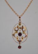 An Art Nouveau 9ct gold garnet drop pendant necklace with large pierced foliate pendant with