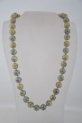 A vintage Chinese cloisonne knotted porcelain bead necklace depicting flowers and clouds with