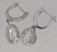 A pair of 925 silver drop earrings with central opalite surrounded by a halo of CZ in a pierced