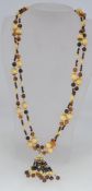 A vintage amber and cream resin bead necklace with filigree metal spacers with tassel dangles and