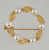 A vintage yellow metal wreath brooch set with pearls and leaves with trombone clasp. Measures 3cms.