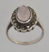 A 925 silver dress ring with central rose quartz cabochon surrouned by a halo of marcasite.