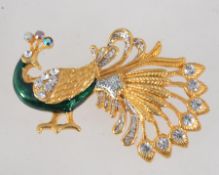 A vintage yellow metal enamelled figural brooch in the form of a peacock with with rhinestone and