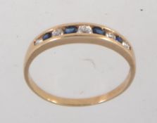 A hallmarked 9ct gold ring with channel set clear and blue stones. Import marks for London. Size P.