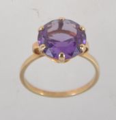 A 9ct gold dress ring set with a large round cut amethyst approx 5cts with hoop shoulders.