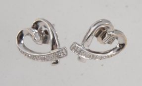 A pair of 9ct white gold and diamond earrings in a heart form with illusion set diamonds with post