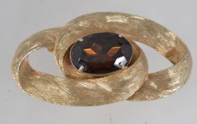 A large 1950s textured gold tone brooch set with a large faux smokey quartz rhinestone with roll