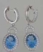 A pair of ladies 20th century silver and blue topaz drop earrings having pave set cz surrounds.