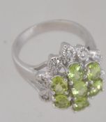 A contemporary ladies silver and peridot stone flower head ring, the oval cut peridots to centre.