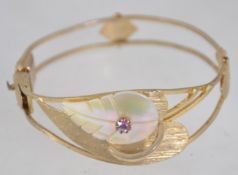 A vintage yellow metal hinge bangle bracelet with modernist leaf motif with central Aurora Borealis