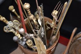 A large collection of brass and copper fireside compendiums held within a vintage barrel