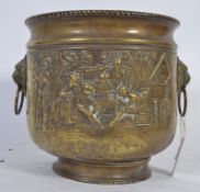 A 19th Century pressed brass planter depicting scenes of jolly men with lion head handles