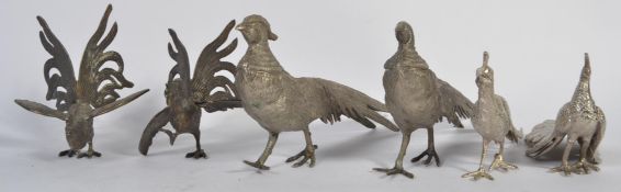 A pair of white metal fighting cocks along with a white metal peacock and pheasants.