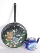 A barge wear painting of cats on a skillet pan along with a painted metal kettle