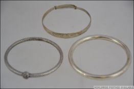 A group of 3 white metal bracelets / ban