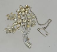 A silver and clear garnet stone brooch in the form of a flower - floral spray. with pin to verso.