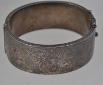 A silver hallmarked rococo chased bangle having clip link and safety chain.