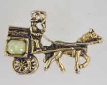 A 1960's brooch in the form of a horse and buggy set with a green glass cabochon.